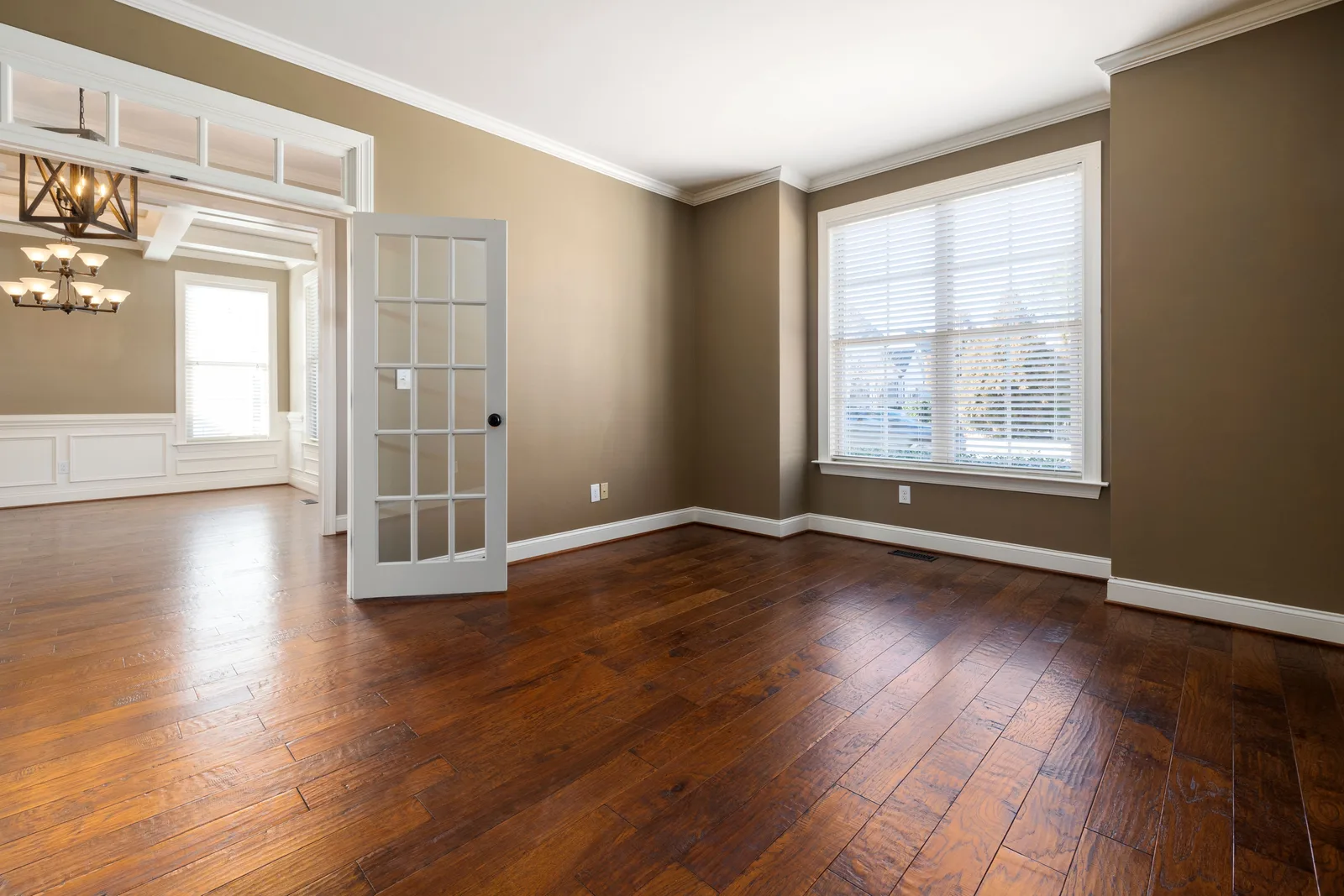 Living room with newly finished solid hardwood flooring, white trim and crown molding