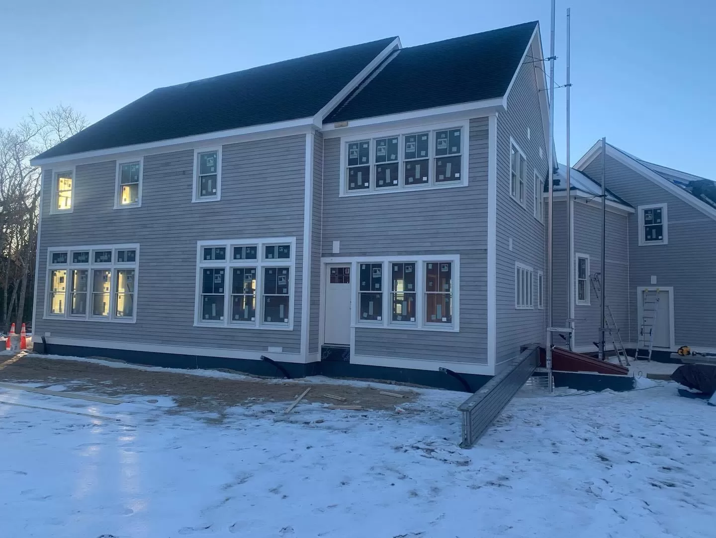 New construction home with gray clapboard siding and white trim completed in winter on Cape Cod by Braun Construction